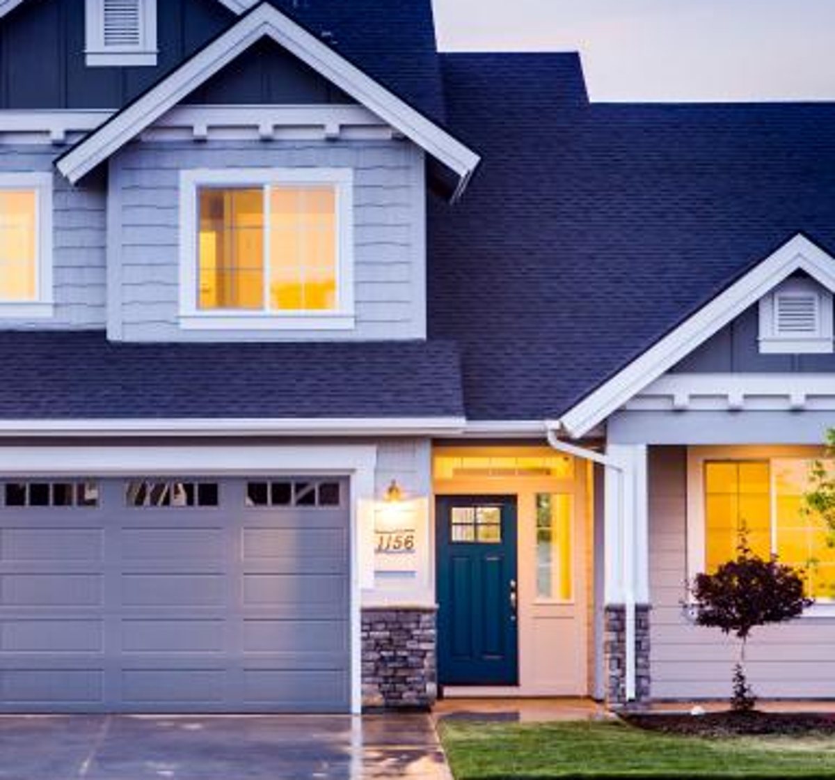 Original listing photo, detail crop of a porch and front door at dusk: soft edges and blurred siding texture.