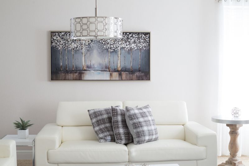 White living room with a cream sofa and framed painting, enhanced sample frame.